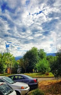 Cars on road against cloudy sky