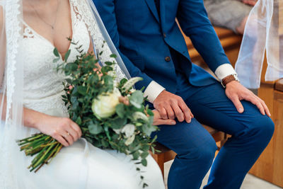 Midsection of couple holding flower bouquet