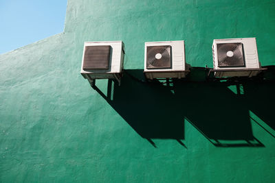 Air conditioning units against a green wall