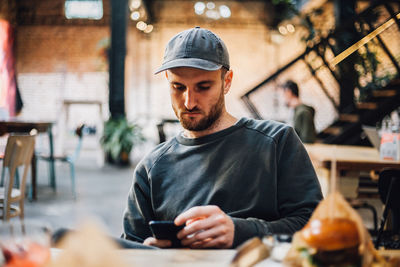 Portrait of young man using mobile phone in cafe