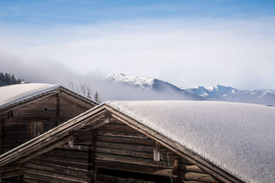 House on snowcapped mountain against sky