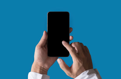 Midsection of man using mobile phone against blue sky