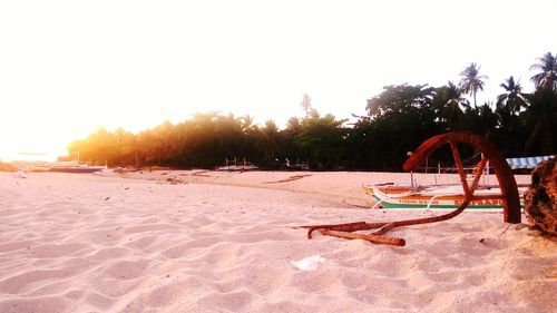 Lounge chairs on sand at beach against clear sky