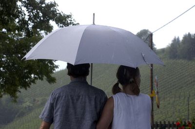 Rear view of people on wet umbrella during rainy season