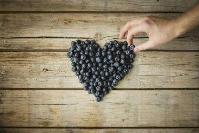 Hand making heart out of blueberries