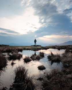 A lonely man staring at the horizon in the middle of the nature with water reflections