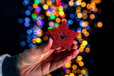 Midsection of person holding illuminated christmas tree at night