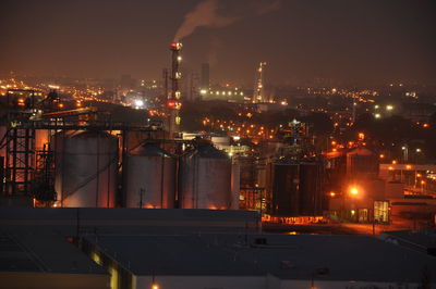 Illuminated factory in city at night