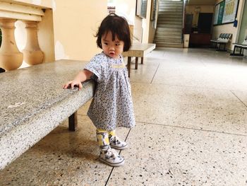 Full length of cute baby girl looking away while standing on tiled floor