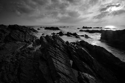 Rocks on beach against sky at dusk