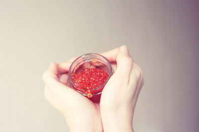 Close-up of hand holding strawberry against white background