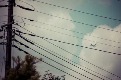 Low angle view of electricity pylon against cloudy sky