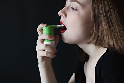 Close-up of woman applying spray in mouth