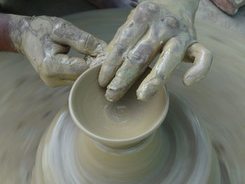 Cropped hands of potter making clay pot at pottery