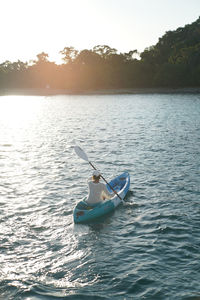 Young adventure lover kayaking in sea against sky sunset, cool activity and nice view 