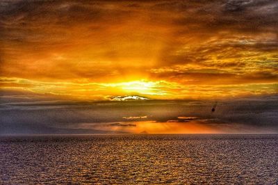 Scenic view of sea against cloudy sky at sunset