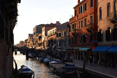 Boats moored in canal amidst buildings in city