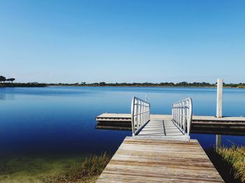 Pier over sea against clear blue sky