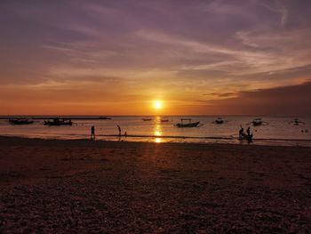 Silhouette people on beach against sky during sunset