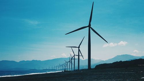 Wind turbines in sea against blue sky