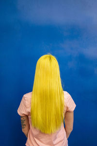 Long hair woman looking at blue wall