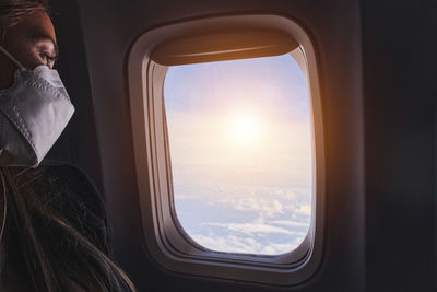 Woman looking at sky with clouds from the airplane window. sunset in the heights.