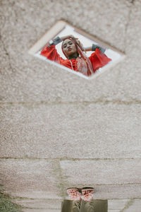 Low section of woman standing on red umbrella