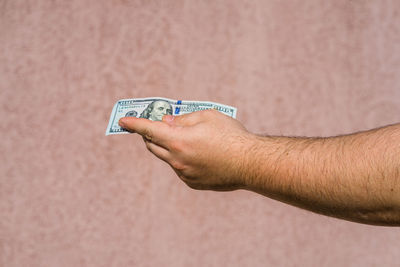 Close-up of man holding hands against wall