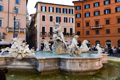 Statue by fountain against buildings in city