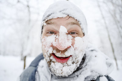 Happy man with snow covered face at winter park