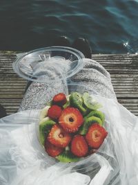 Low section of woman with fruits in box on pier over sea