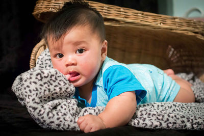 Portrait of cute baby boy lying on bed at home