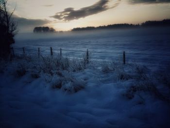 Snow covered field at sunset