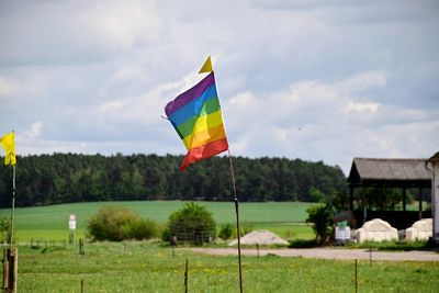 Multi colored flag on field against sky