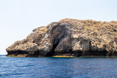 Rock formations by sea against clear sky