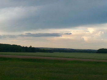 Scenic view of grassy field against cloudy sky