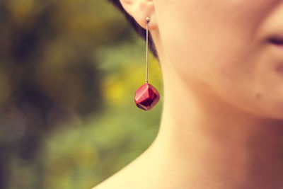 Cropped image of young woman wearing red earring