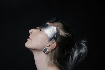 Profile view of young woman wearing headdress against black background