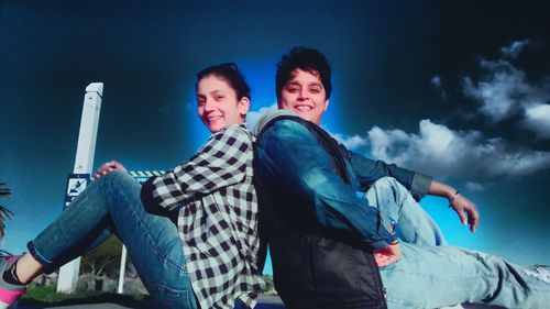 Low angle view of friends against cloudy sky