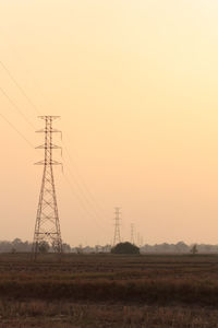 Electricity pylon on field against sky during sunset