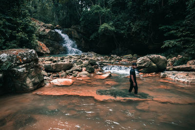 Man standing in river at forest