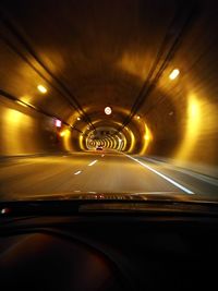 Illuminated tunnel seen through car windshield