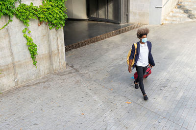 Top view of black man in a suit walking with suitcase on the street