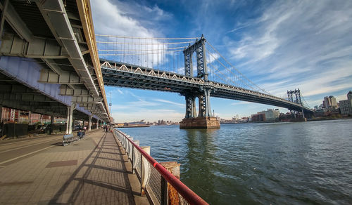 Low angle view of manhattan bridge over east river against blue sky
