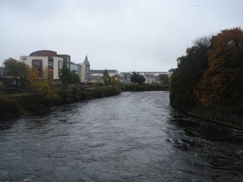 Canal amidst trees against sky