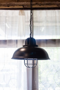 Close-up of electric lamp hanging against ceiling