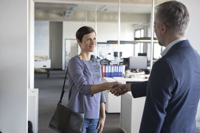 Businessman and businesswoman shaking hands in office