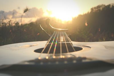 Close-up of guitar against sky during sunset