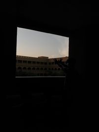 Silhouette buildings against sky seen through window