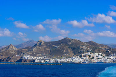 Scenic view of sea by buildings against blue sky